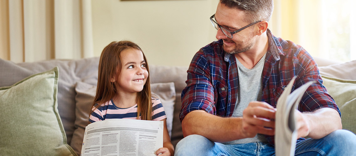 Father and daughter looking at newspaper