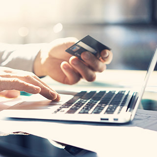 Close up of person using credit card and laptop