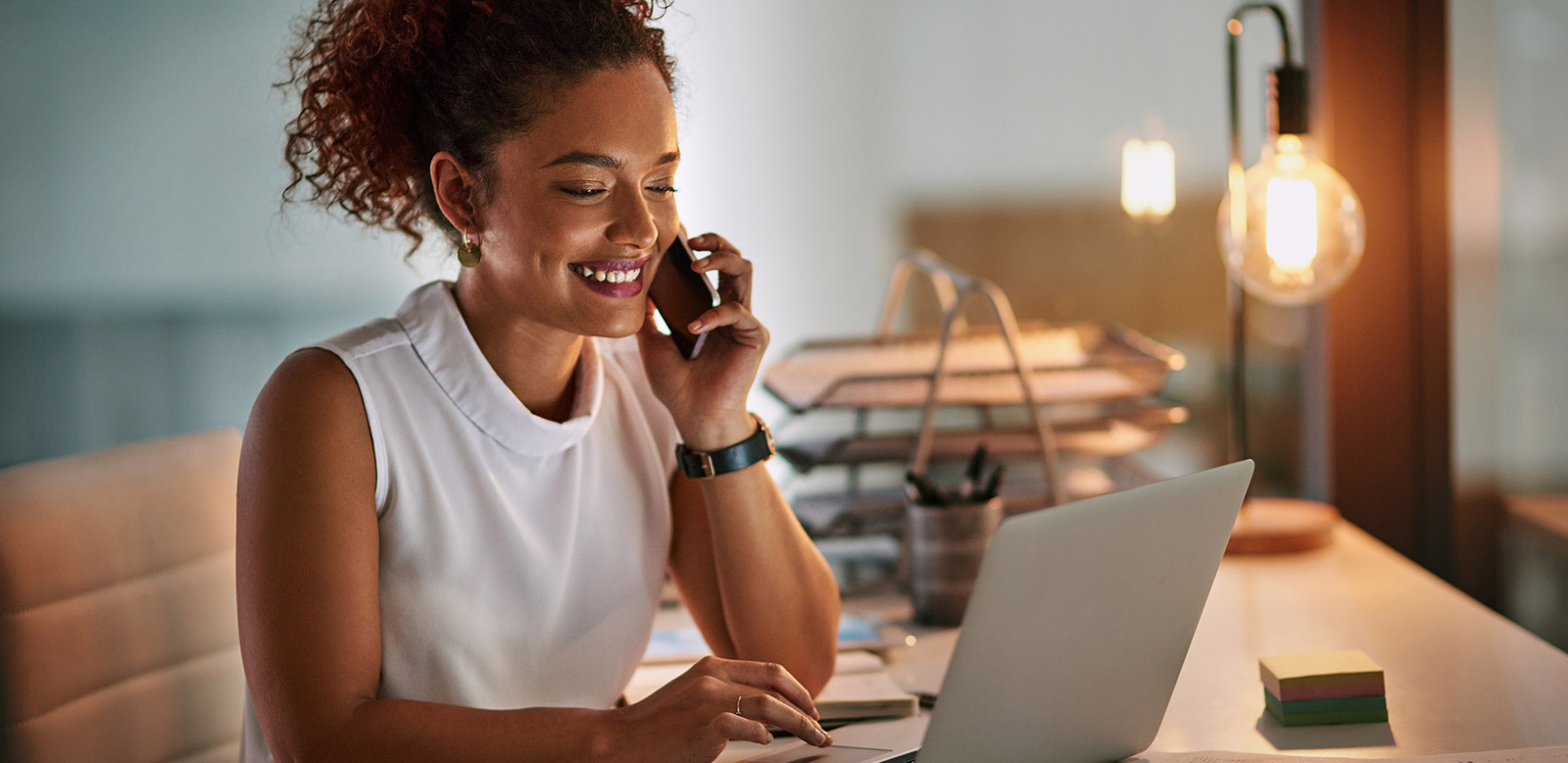 Young woman on phone while using laptop